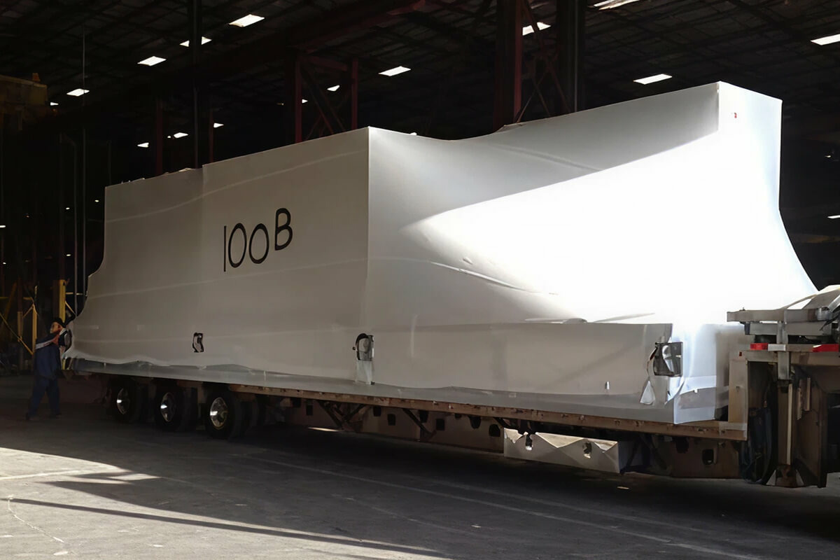 Large industrial equipment wrapped in Griff-Shrink heat-shrinkable protective film on a flatbed trailer inside a warehouse